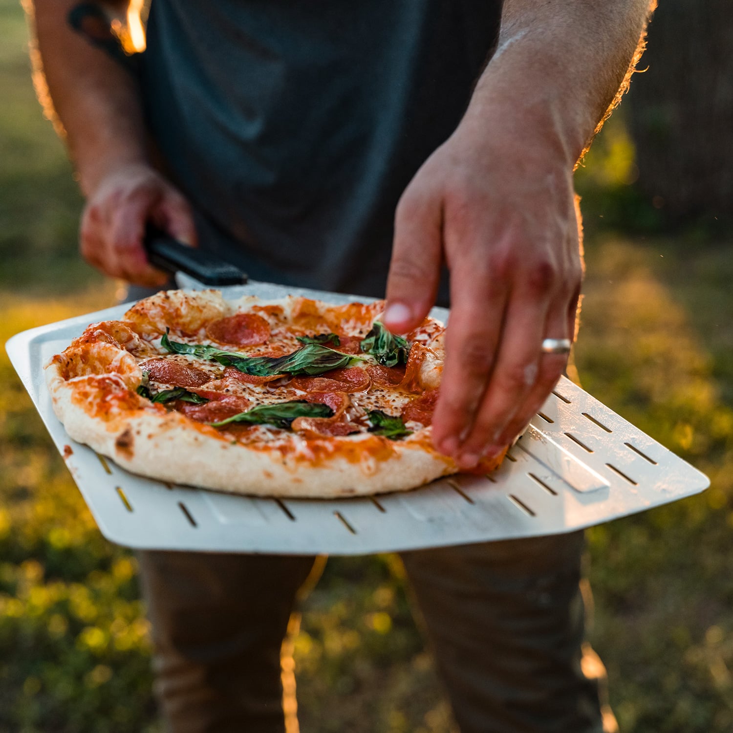 Ooni Pizzaschieber mit frischer Pizza, gehalten von Männerhand