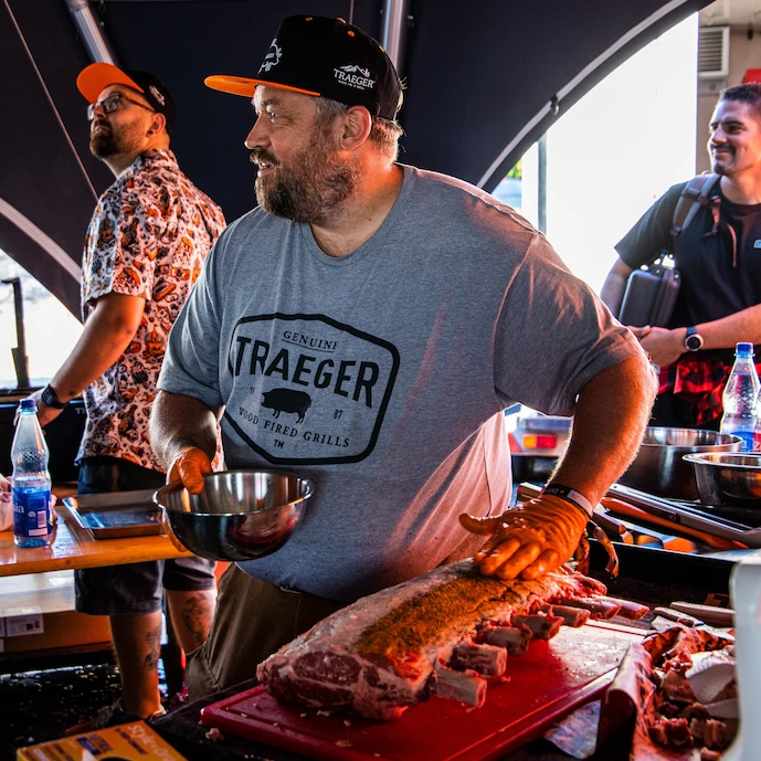 Mann beim Auftragen des Rubs auf ein Stück Fleisch