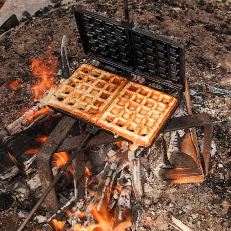 Ein Waffeleisen auf einem offenen Feuer mit Waffeln darin