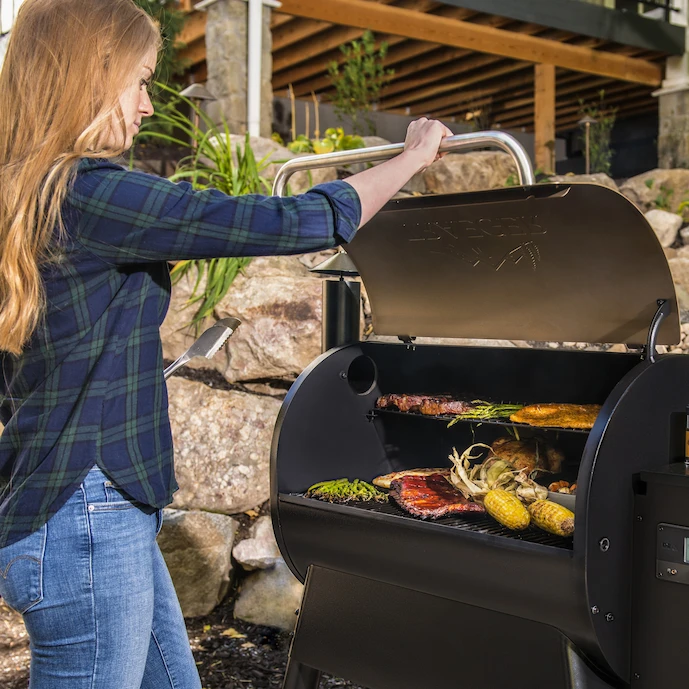 Frau beim Öffnen eines TRAEGER-Grills.