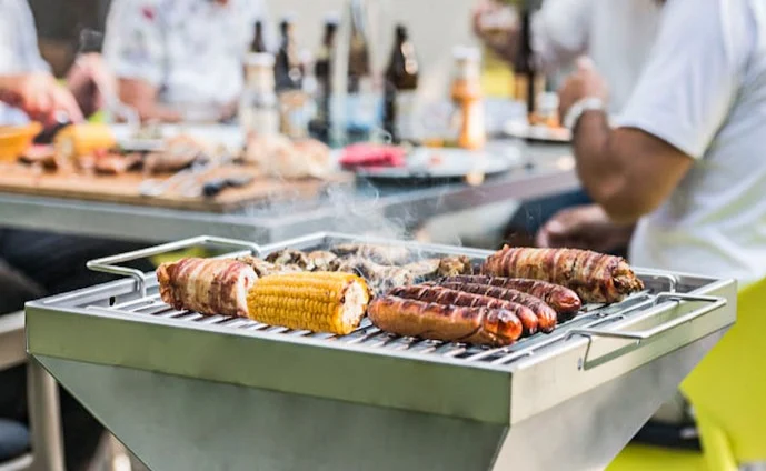 Thüros Säulengrill im Einsatz im Hintergrund ein Tisch mit Gästen